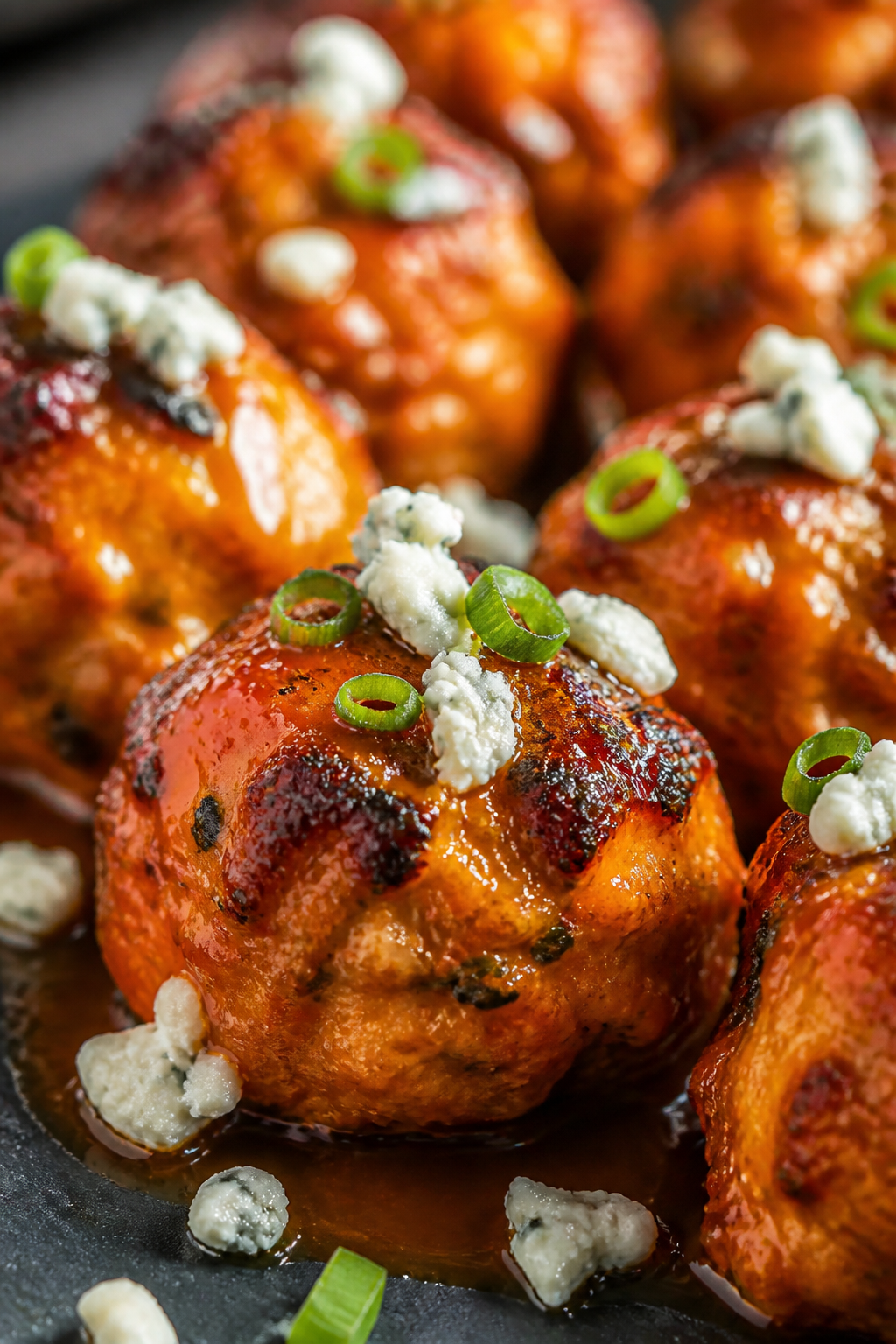 Close-up detail: Juicy oven-baked Buffalo turkey meatballs just tossed in glossy orange-red sauce, b