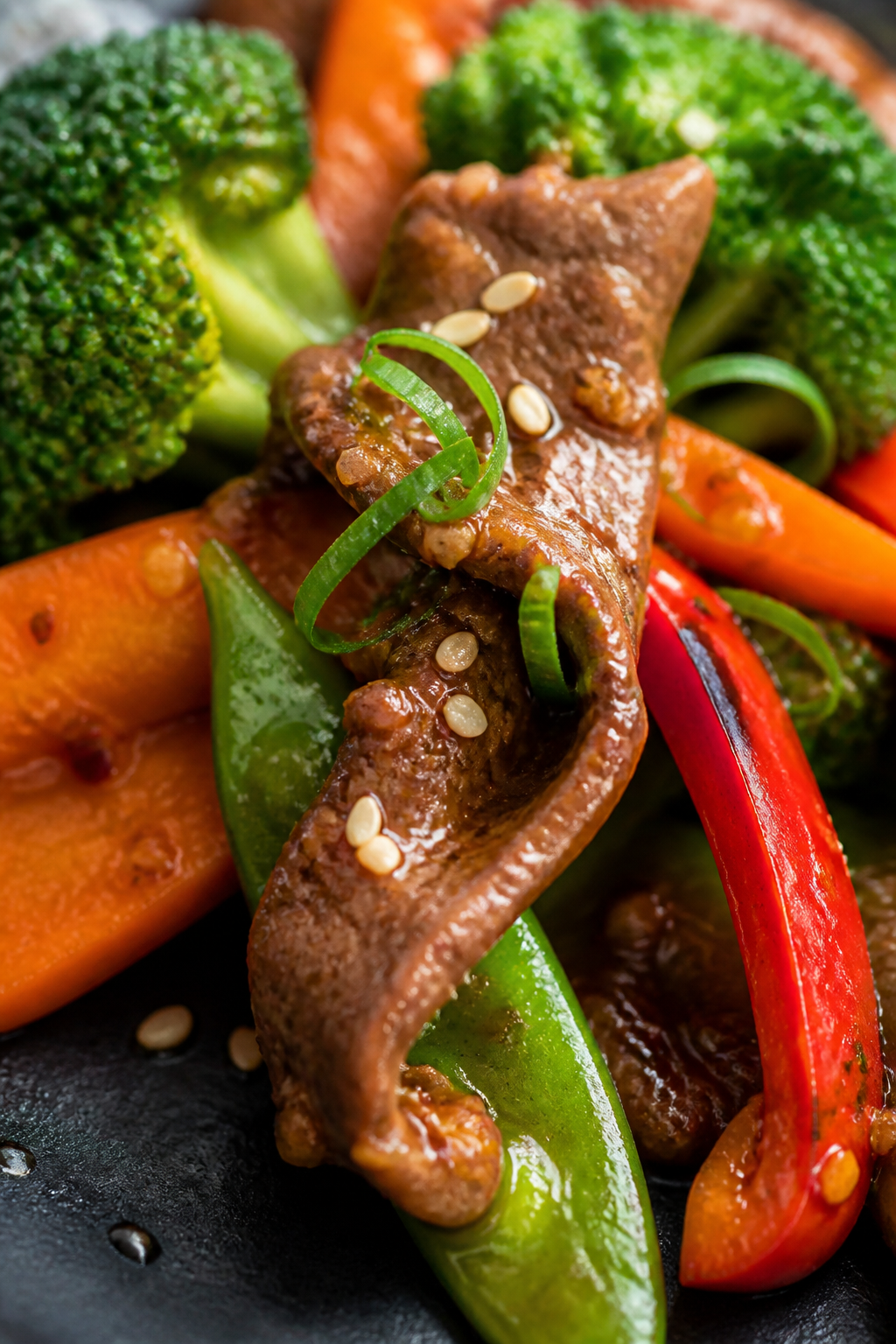 Close-up detail, texture-forward: Ultra-close shot of lacquered beef strip curled atop a snap pea an
