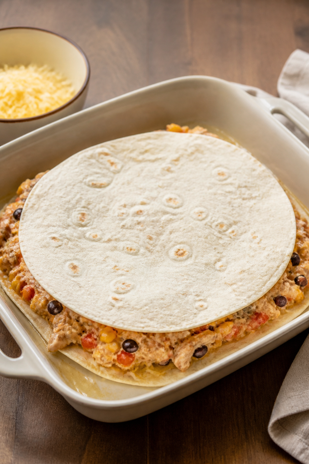 Cooking process shot: the second tortilla layer being pressed gently over the first cheese-and-filli
