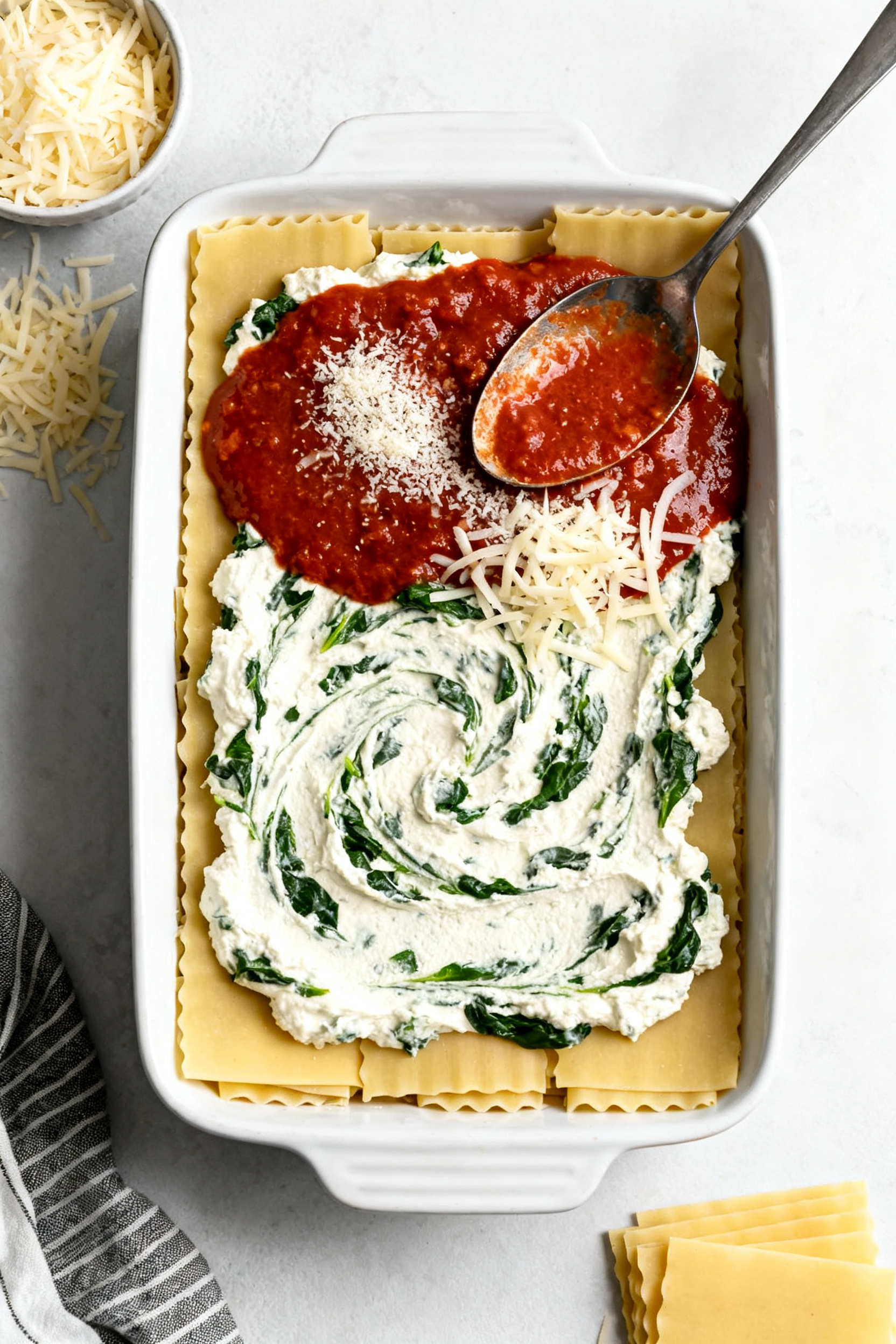 Tasty top view: Overhead shot of the layered lasagna mid-assembly in a 9x13 dish—par-cooked noodle