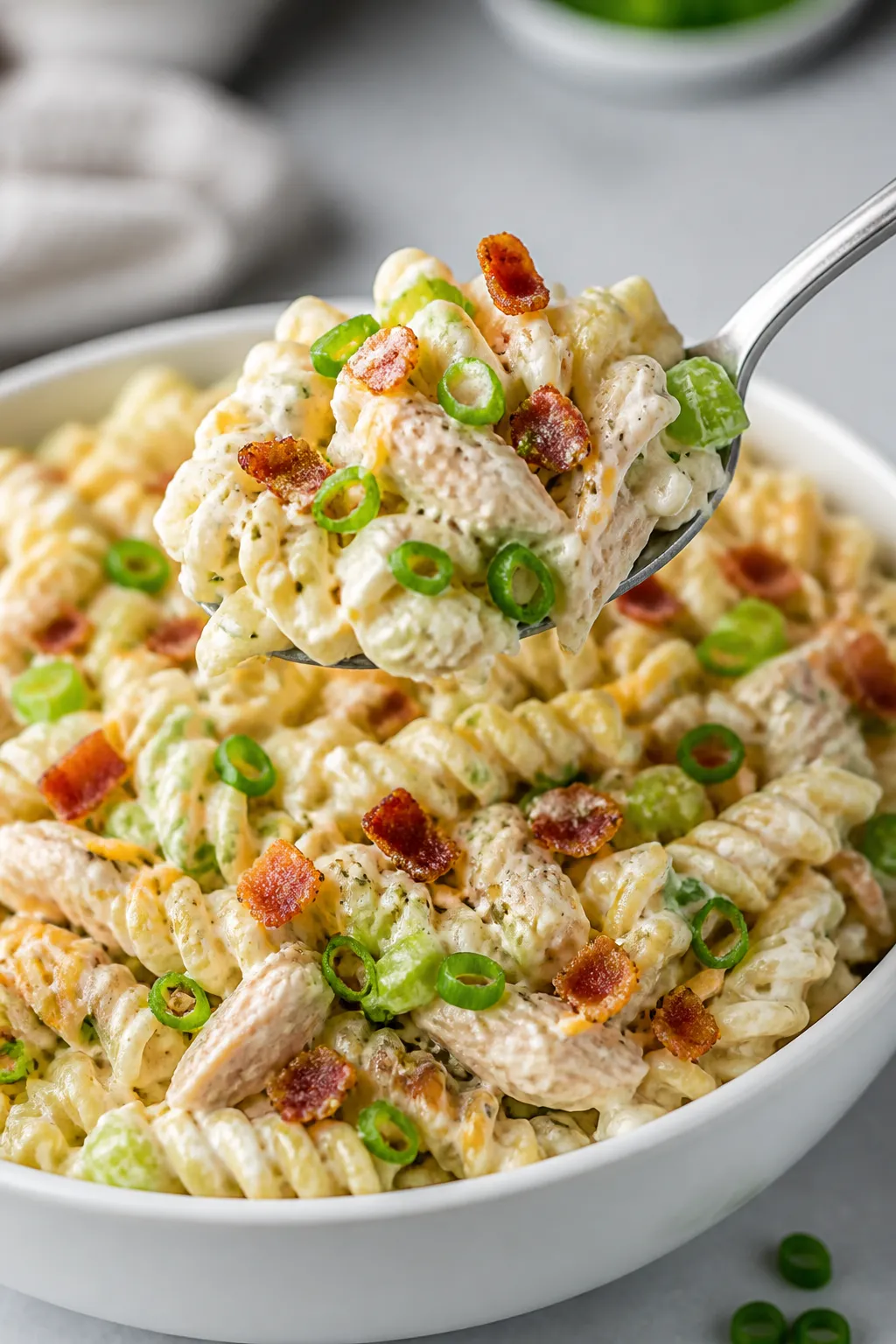 Close-up detail: A heaping spoonful of chilled Crack Chicken Pasta Salad being lifted from a bowl, s