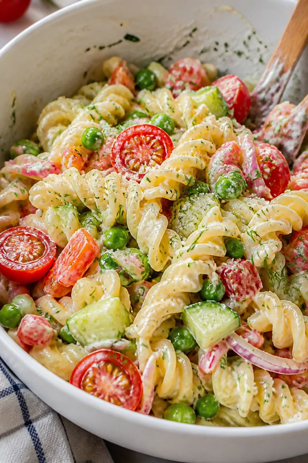 Close-up detail: Tossed cottage cheese pasta salad mid-combine in a large white mixing bowlārotini