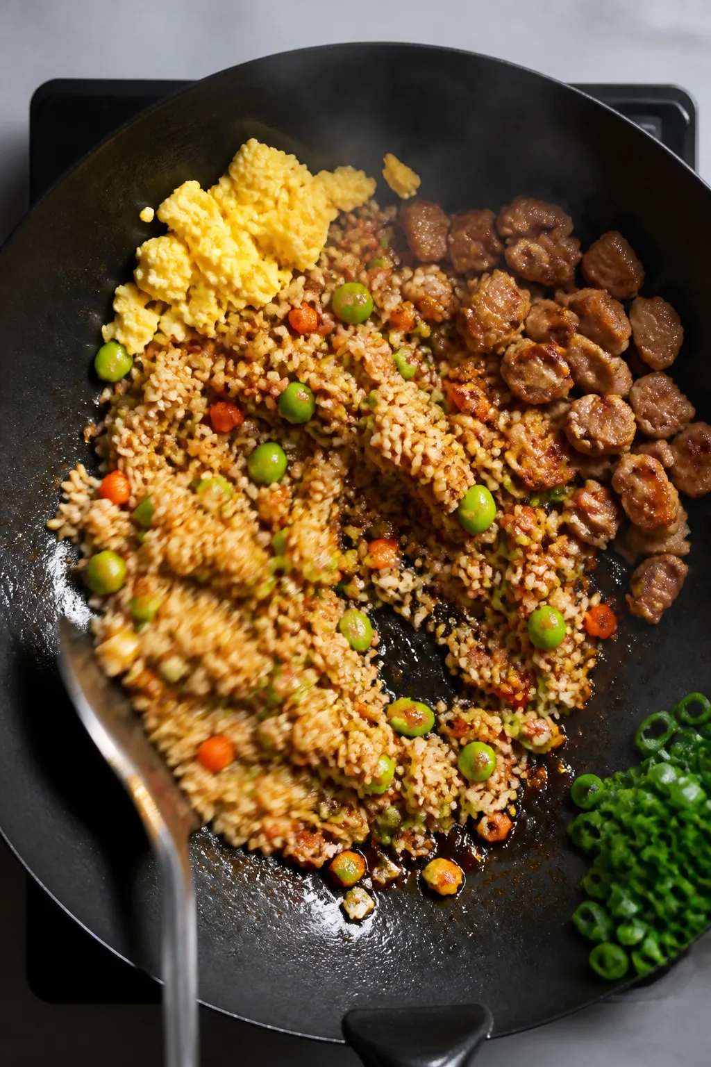 Cooking process: Overhead shot of pork fried rice mid-toss in a carbon-steel wok on high heat—rice