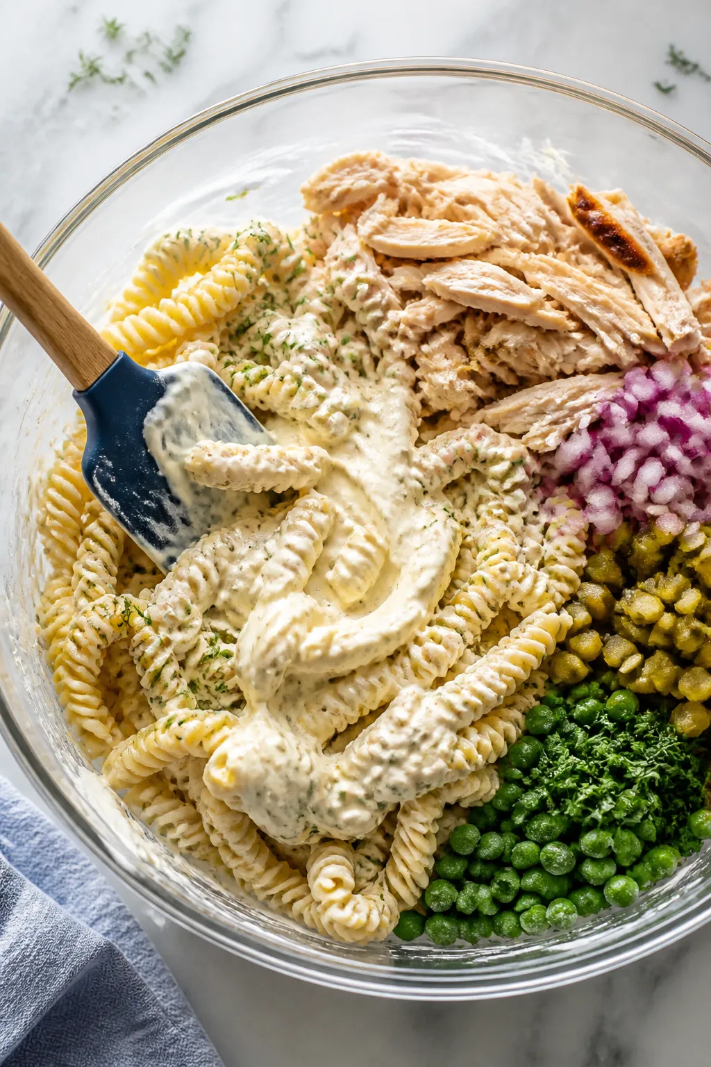 Cooking process: Tossing stage in a large mixing bowl—cooled, just-warm rotini being folded with t