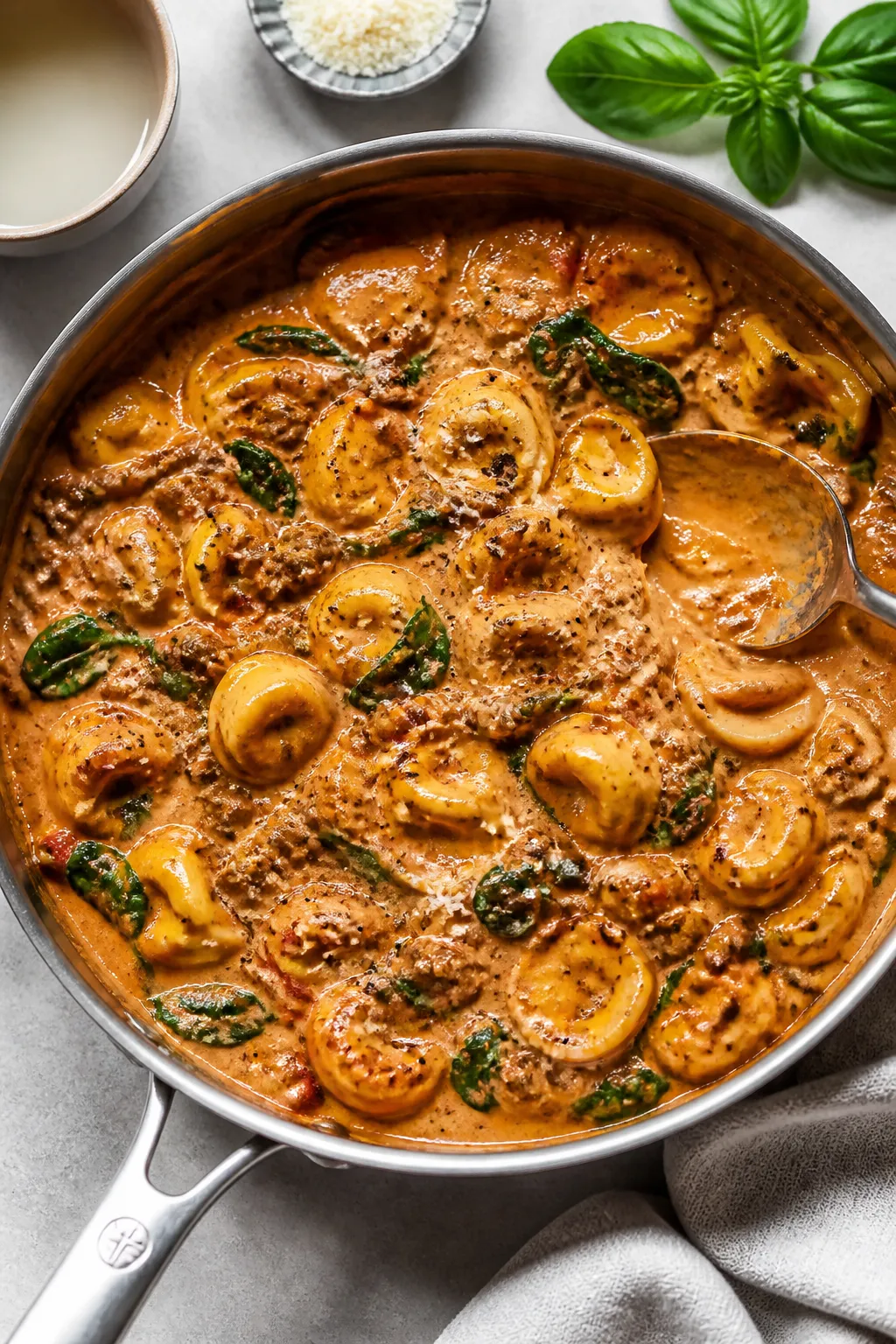 Creamy toss moment: Overhead shot of cheese tortellini just folded into the tomato-cream beef sauce
