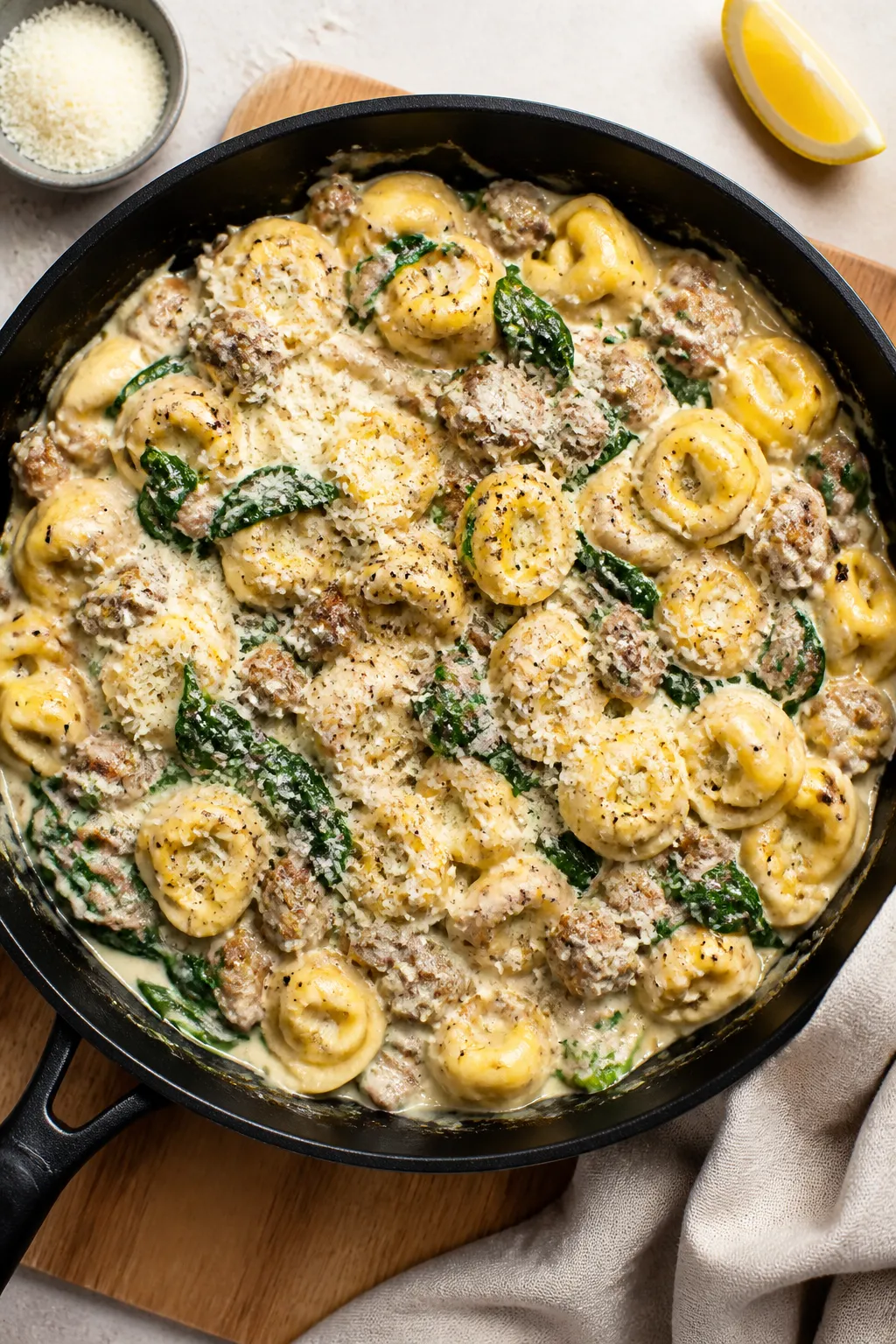 Overhead “one-pan” beauty shot: of creamy Garlic Parmesan Sausage Tortellini in a large black sk