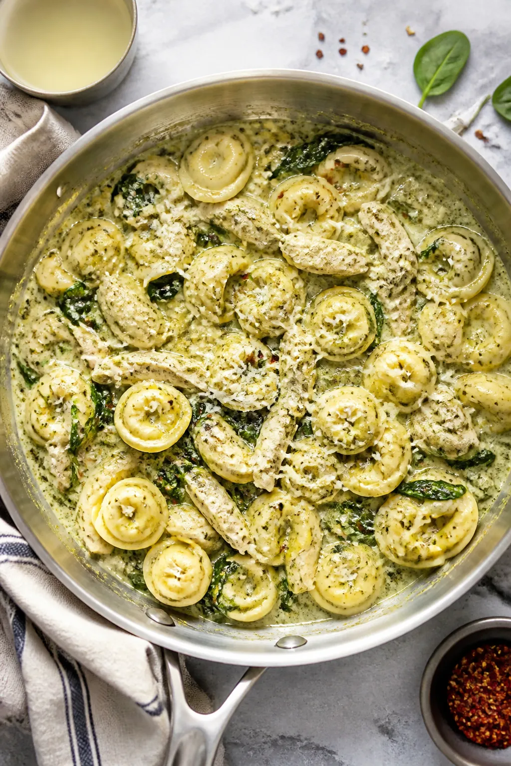 Tasty top view: Overhead shot of creamy pesto chicken tortellini being gently tossed together in a w