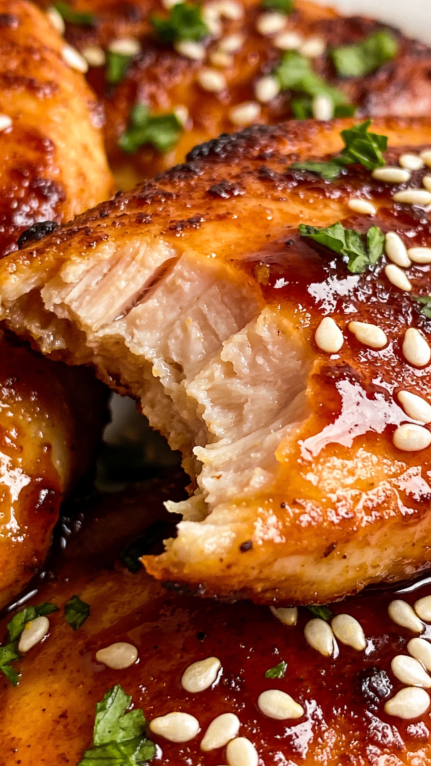 A close-up, ultra-close angle from above or slightly to the side showcasing the juicy texture and glossy sauce; focus on a bite with the tender interior contrasted by a perfectly browned crust, sesame seeds or chopped parsley scattered on top for color, vibrant colors, premium food-blog styling, bright natural lighting, shallow depth of field, food dominating frame.