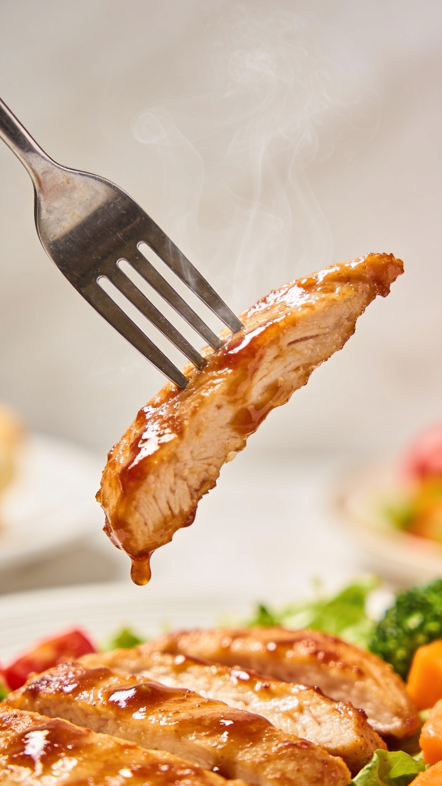 A dynamic action close-up capturing the perfect bite moment: a fork lifting a juicy, ultra-juicy chicken strip with glossy glaze mid-air just before reaching the mouth, sauce trailing slightly, steam wisps, premium food-blog styling, bright natural lighting, shallow depth of field, 90–95% frame fill, no hands or faces visible.